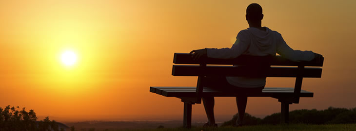 man on bench overlooking sunset